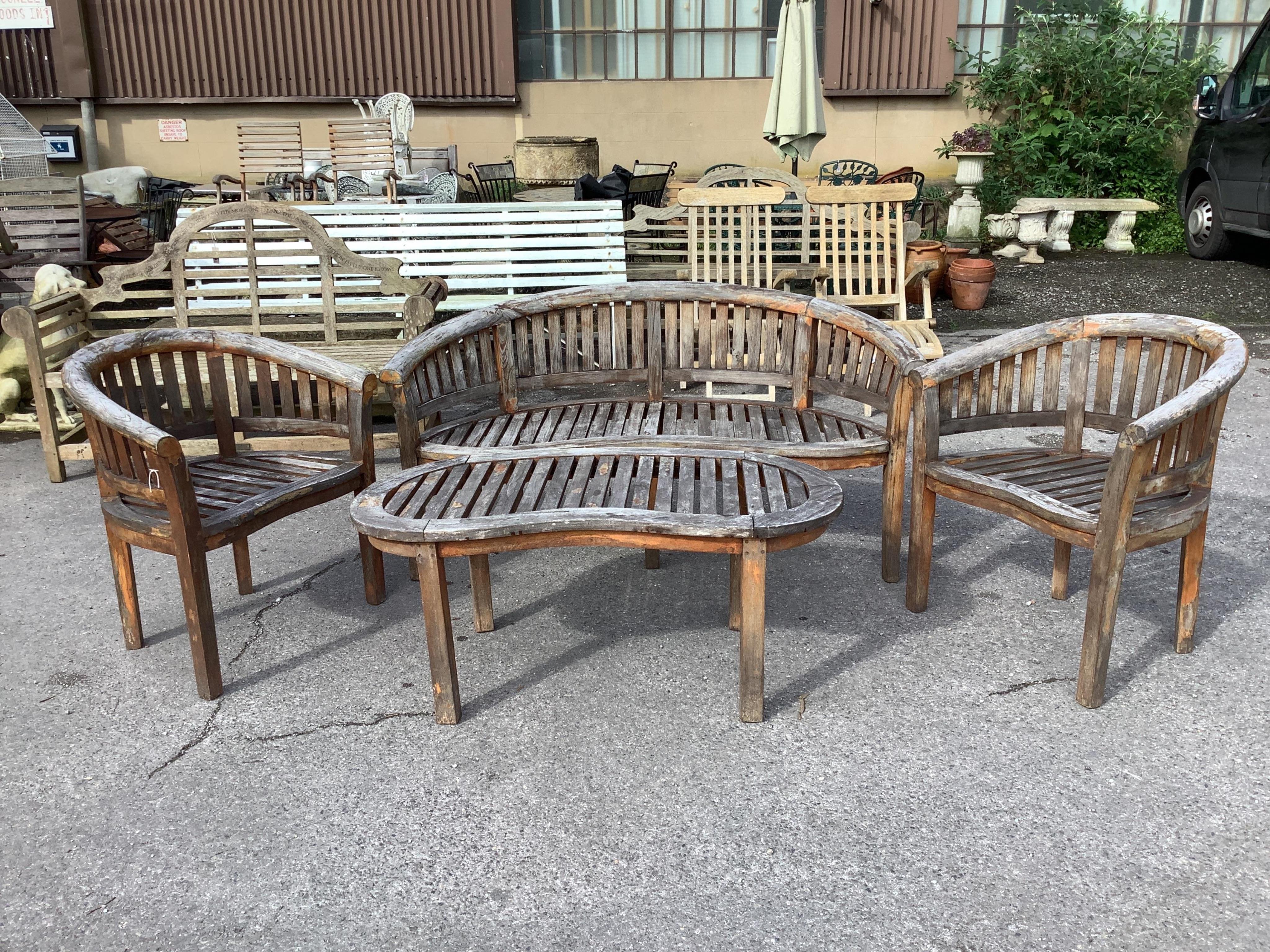 A weathered teak garden 'banana' bench, width 150cm, depth 60cm, height 84cm, a pair of chairs and coffee table